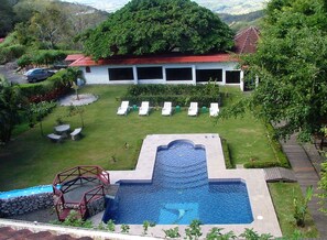 Relax by the rectangular pool with a decorative edge and waterfall feature, surrounded by lounge chairs and lush greenery.