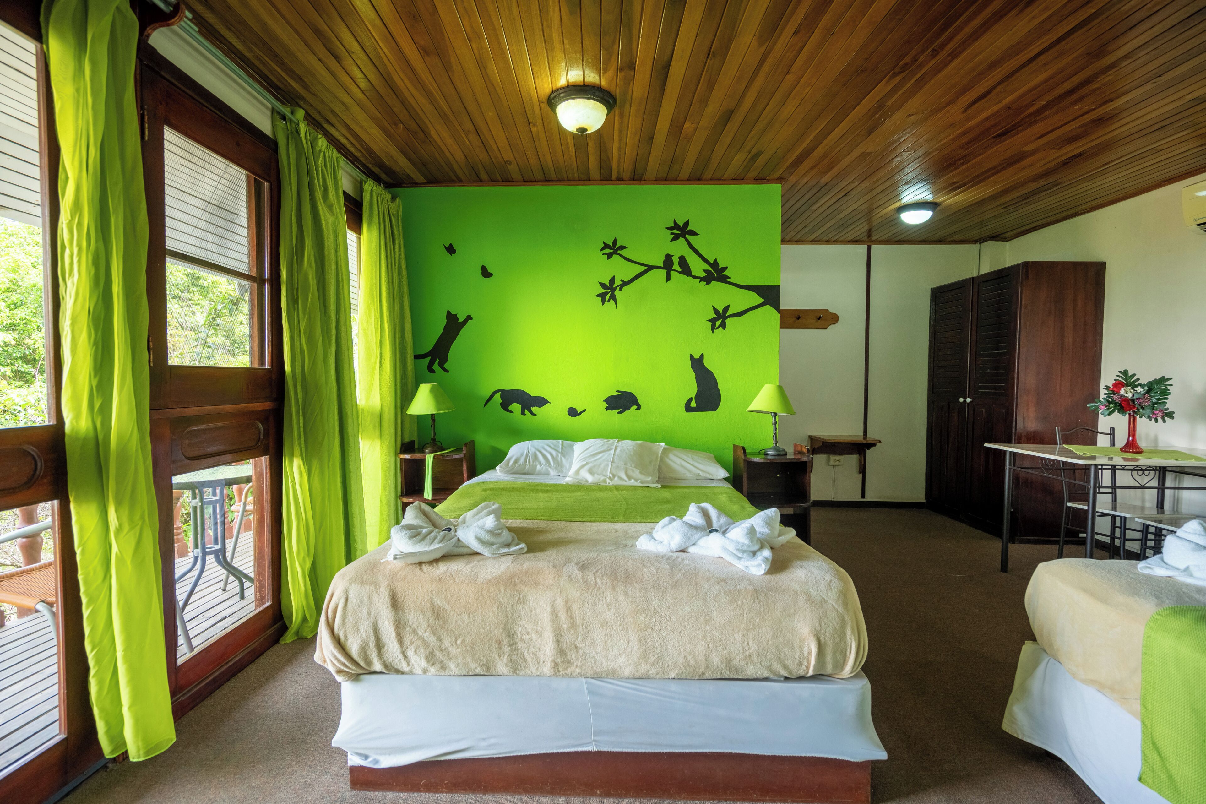 A room with a bed, two bedside tables, a desk, and a chair.