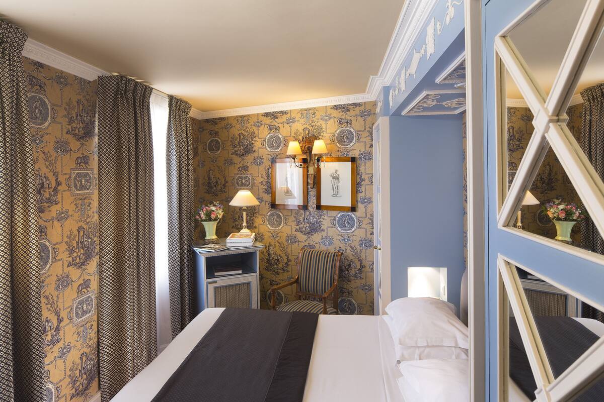 Ein Hotelzimmer mit Bett, Sessel, Schreibtisch und Spiegel.