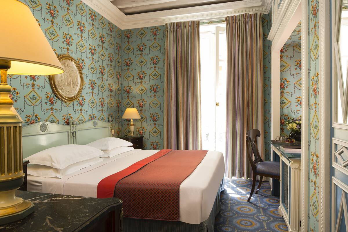 Ein Hotelzimmer mit Bett, Schreibtisch, Stuhl und Lampe.