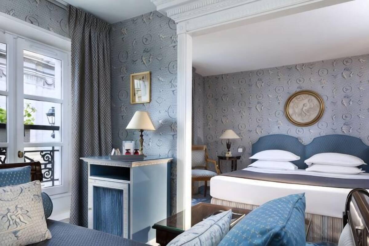 Ein Hotelzimmer mit Bett, Schreibtisch, Stuhl, Fenster und einer Wand mit einem Muster.