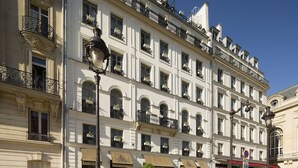 A multi-story building with balconies, awnings, and a street lamp. - Hôtel Des Grands Hommes (Paris)