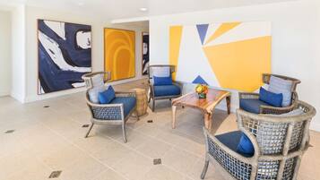 A lobby with wicker chairs, a wooden coffee table, and abstract wall art.