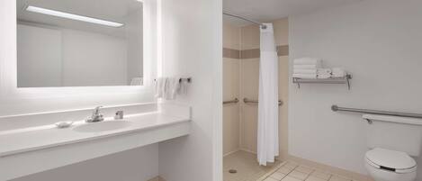 Un baño moderno con un espejo grande, un lavabo blanco y una ducha con cortina blanca.