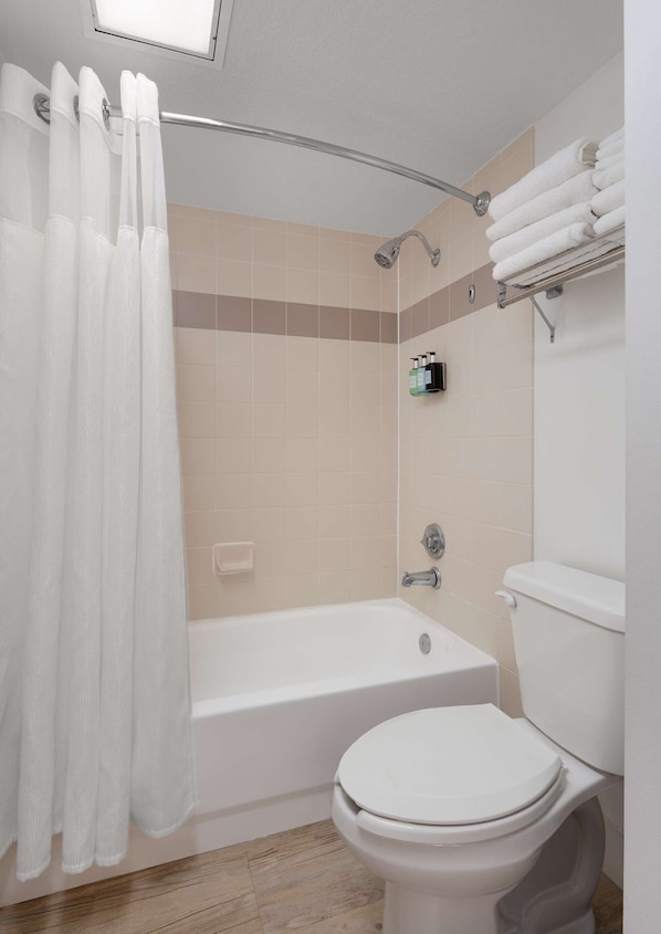 Un baño con bañera, inodoro y cortina de ducha.