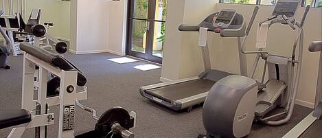 Un gimnasio con cintas de correr, máquinas de pesas y una pantalla de televisión.
