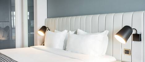 A neatly made bed with white linens, two bedside lamps, and a magazine on the nightstand.