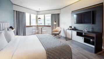 Habitación de hotel con una cama grande, televisor, escritorio y una silla.