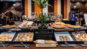A buffet with various food items, a plant centerpiece, and a coffee machine in the background. - HF Ipanema Porto (Porto)