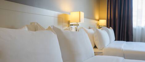 Hotellihuone, jossa on suuri sänky, yöpöytä ja lamppu.