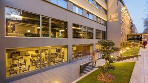 A modern hotel with multiple dining areas visible through large windows, a well-lit exterior, and a staircase leading to the entrance. - HF Tuela Porto (Porto)