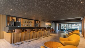A modern bar area with wooden accents, seating, and a view of the city. - HF Tuela Porto (Porto)