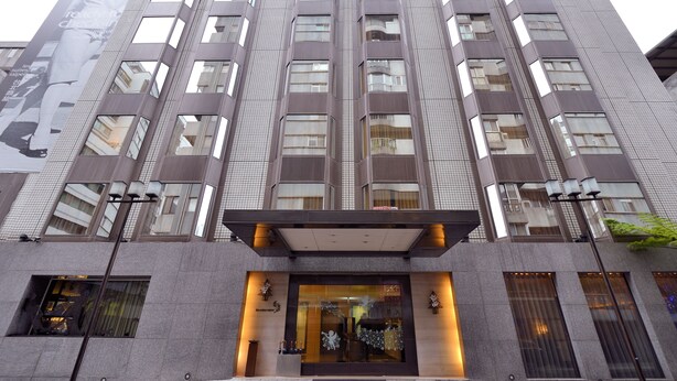 Un edificio alto y moderno con una amplia entrada de vidrio y un anuncio llamativo en la fachada.