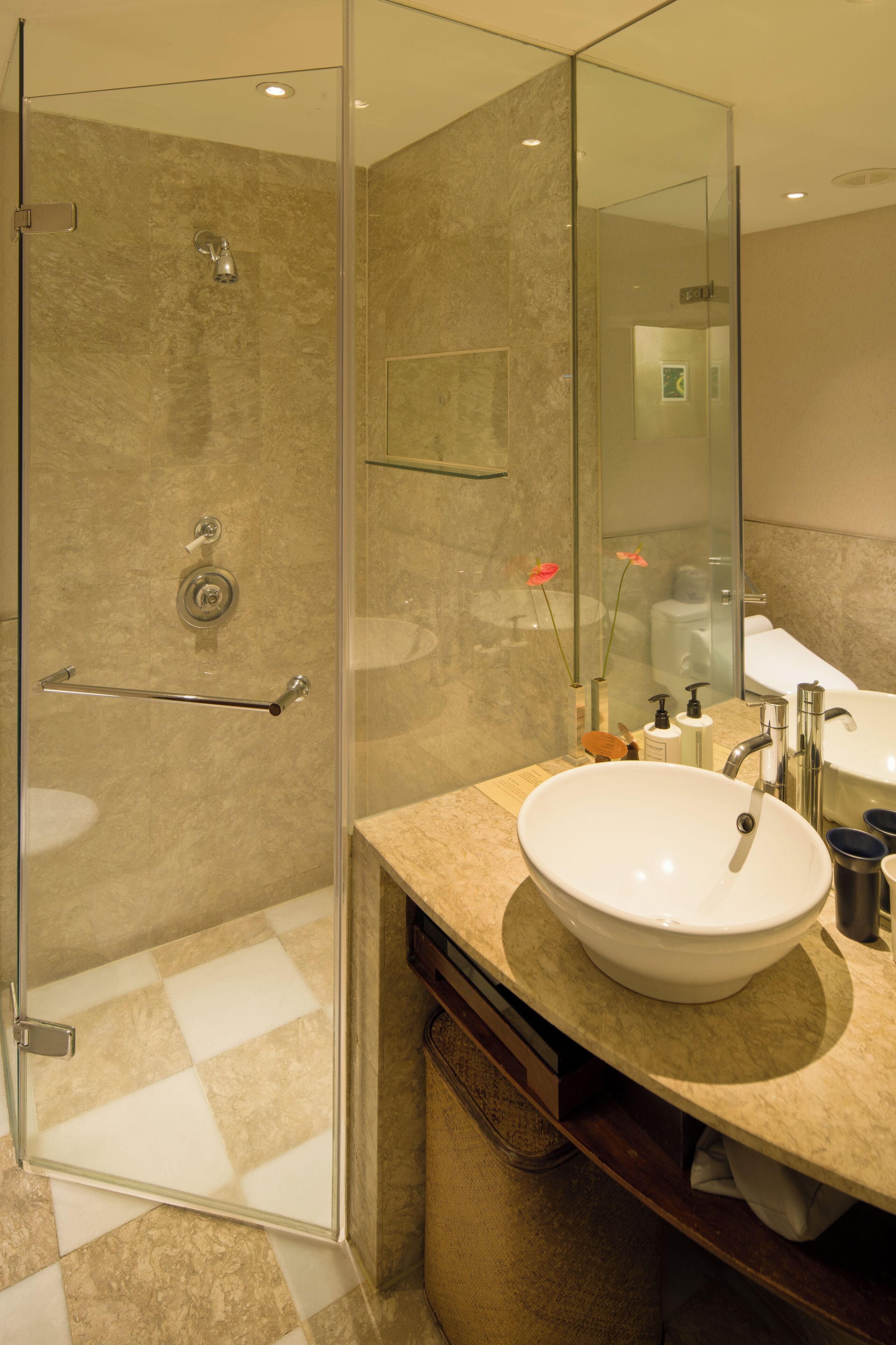Un baño moderno con ducha de vidrio, lavamanos amplio y espejo.