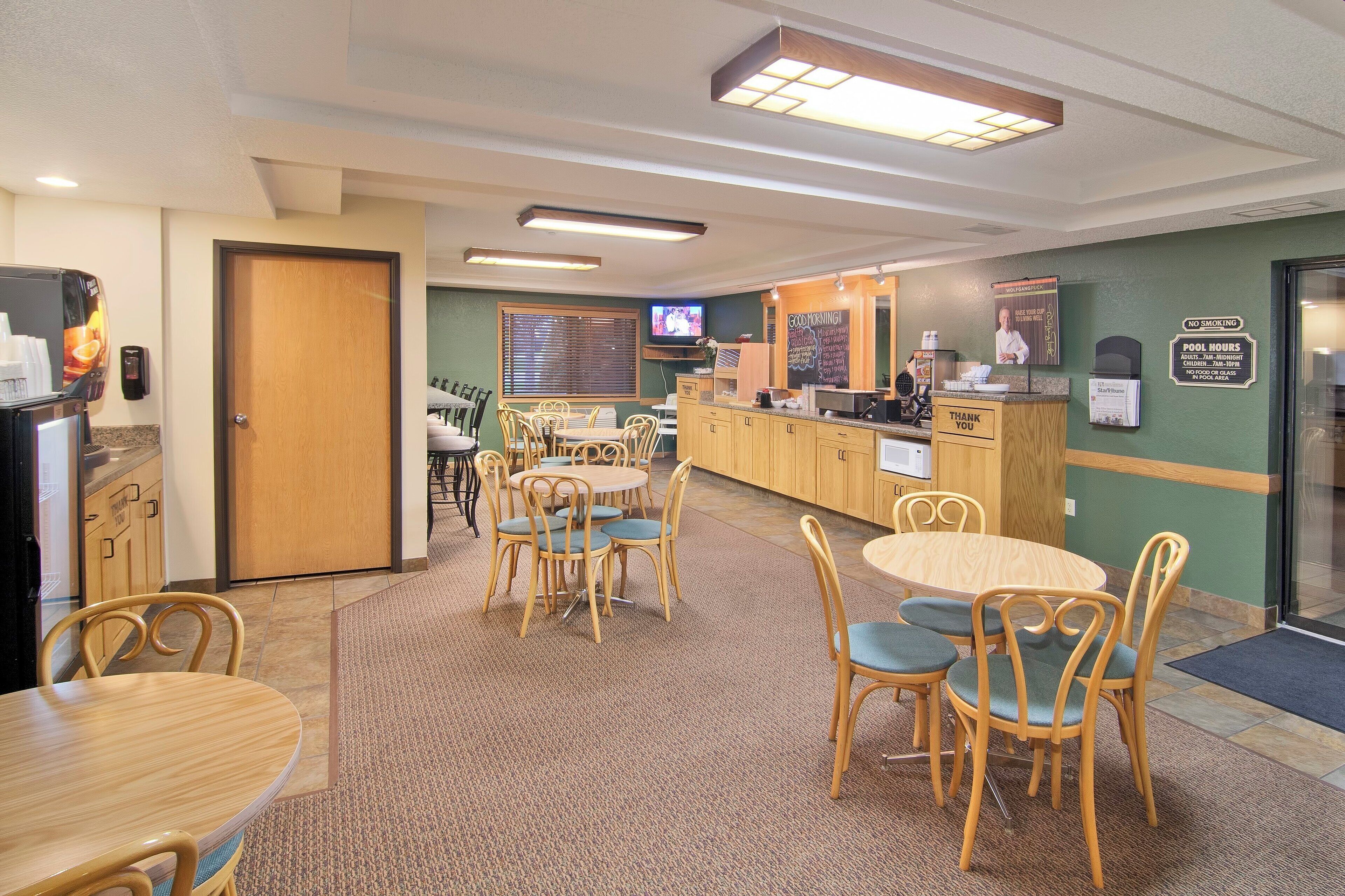 A hotel lobby with multiple seating areas, a reception desk, and a television screen.