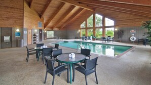 Zona de piscina con techo de madera, mesa de billar y mobiliario exterior.