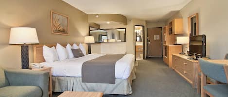 Habitación de hotel con cama, escritorio, silla, lámpara, televisor y cómoda.