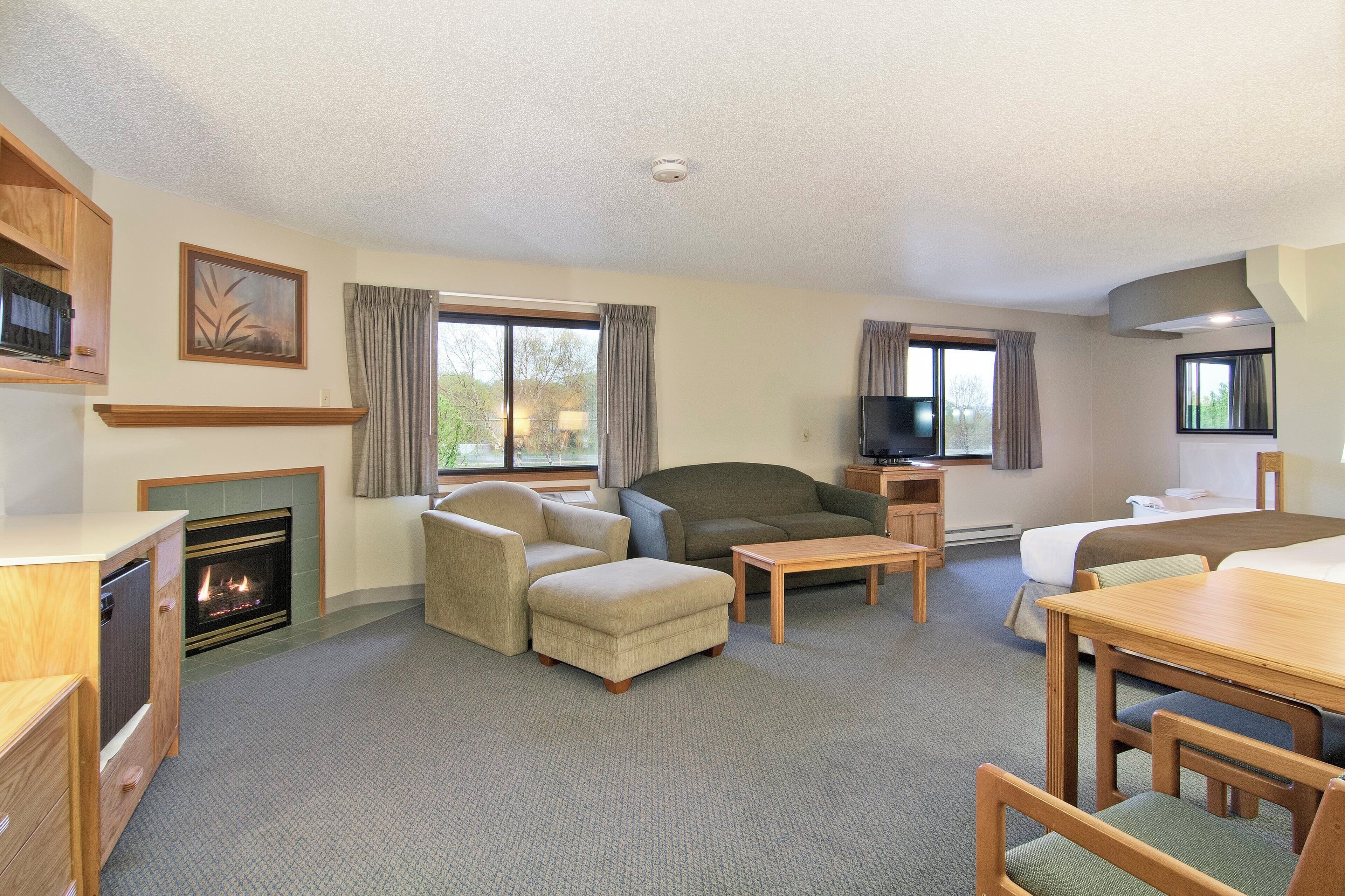 A hotel room with a fireplace, a sofa, a dining table, and a TV.