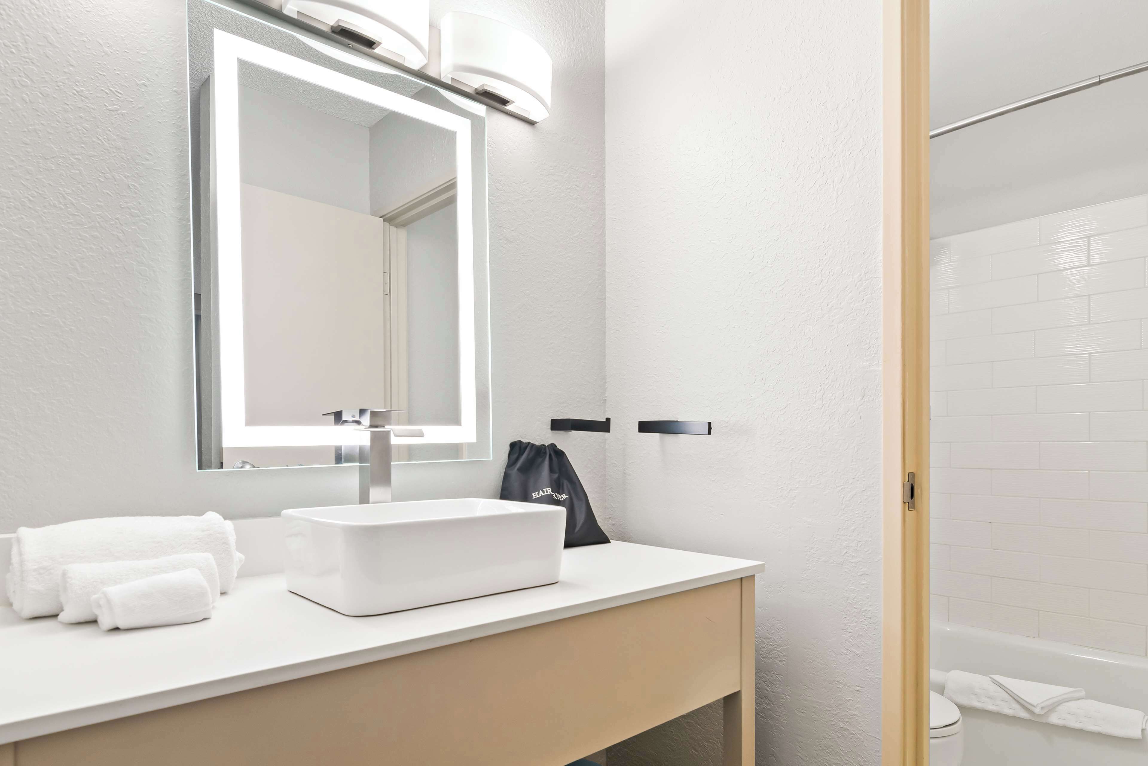 A modern bathroom with a white sink, mirror, and towel rack.