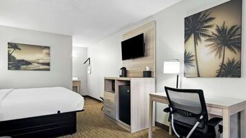 Habitación de hotel con cama, escritorio, silla, televisión y obras de arte.