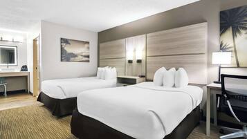 A hotel room with two beds, a desk, a chair, and a painting on the wall.
