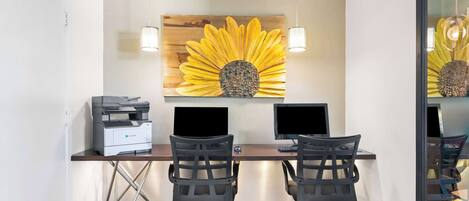 Una oficina moderna con dos escritorios, sillas, una gran obra de arte de girasol e impresora.