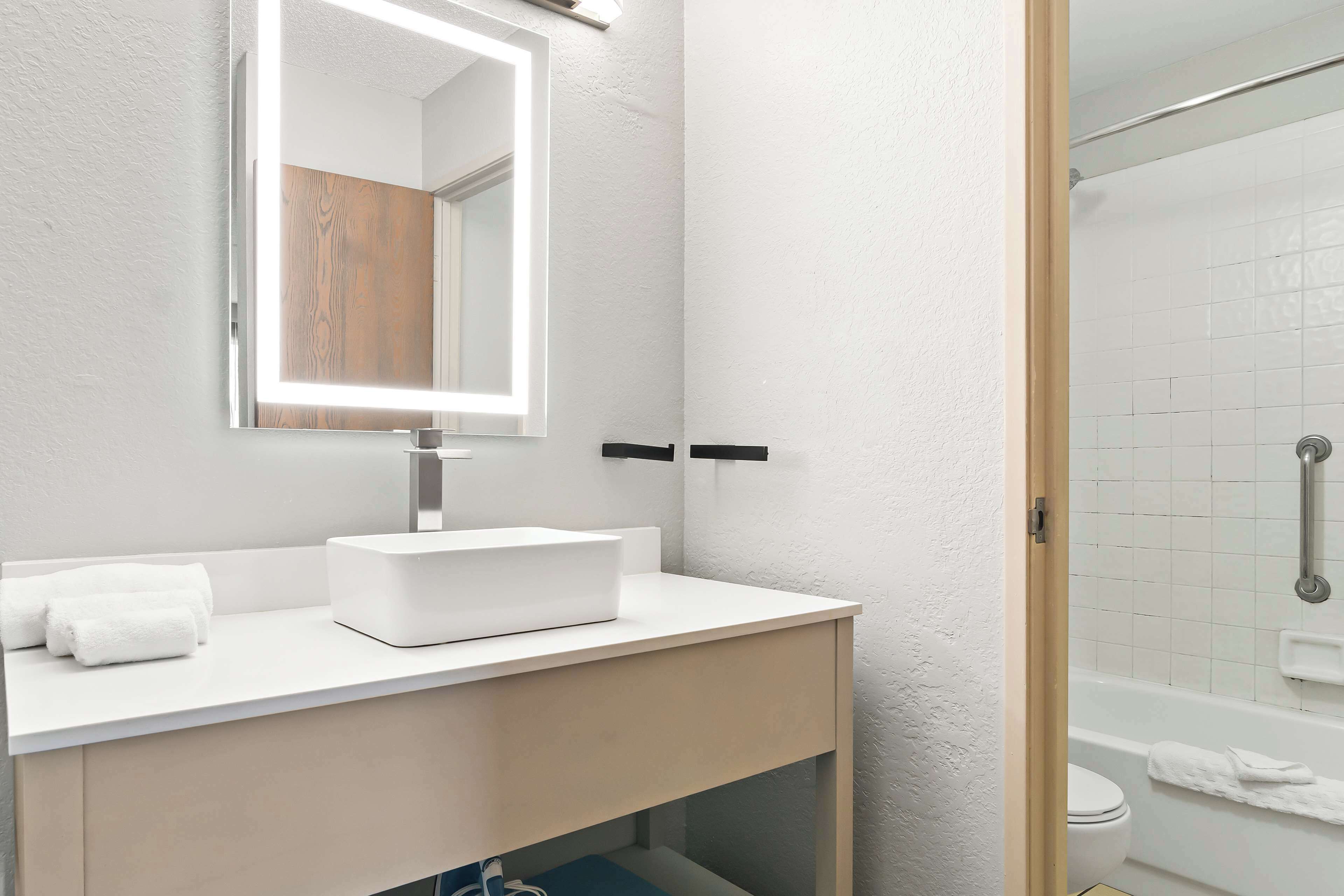 A bathroom with a white sink, mirror, and towel rack.