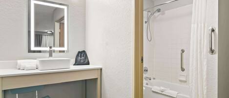 A bathroom with a sink, mirror, towel rack, and a shower area with a glass door.