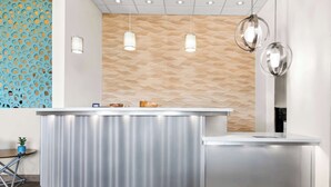 Un área de recepción con diseño moderno, que incluye una pared con textura, un mostrador de recepción e iluminación colgante.