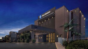 Un hotel moderno con un llamativo letrero de 'Best Western', un acceso cubierto y un estacionamiento.