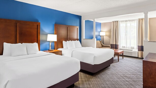 A hotel room with two beds, a desk, a chair, and a large window with curtains. - Comfort Inn & Suites Walterboro I-95 (Walterboro)
