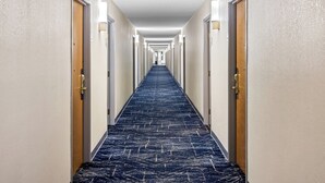 A hotel hallway with a blue carpet, white walls, and doors on both sides. - Comfort Inn & Suites Walterboro I-95 (Walterboro)