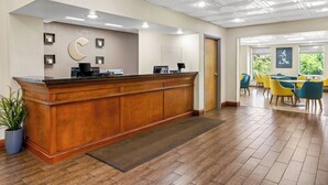 A reception area with a wooden counter, a potted plant, and a tiled floor. - Comfort Inn & Suites Walterboro I-95 (Walterboro)