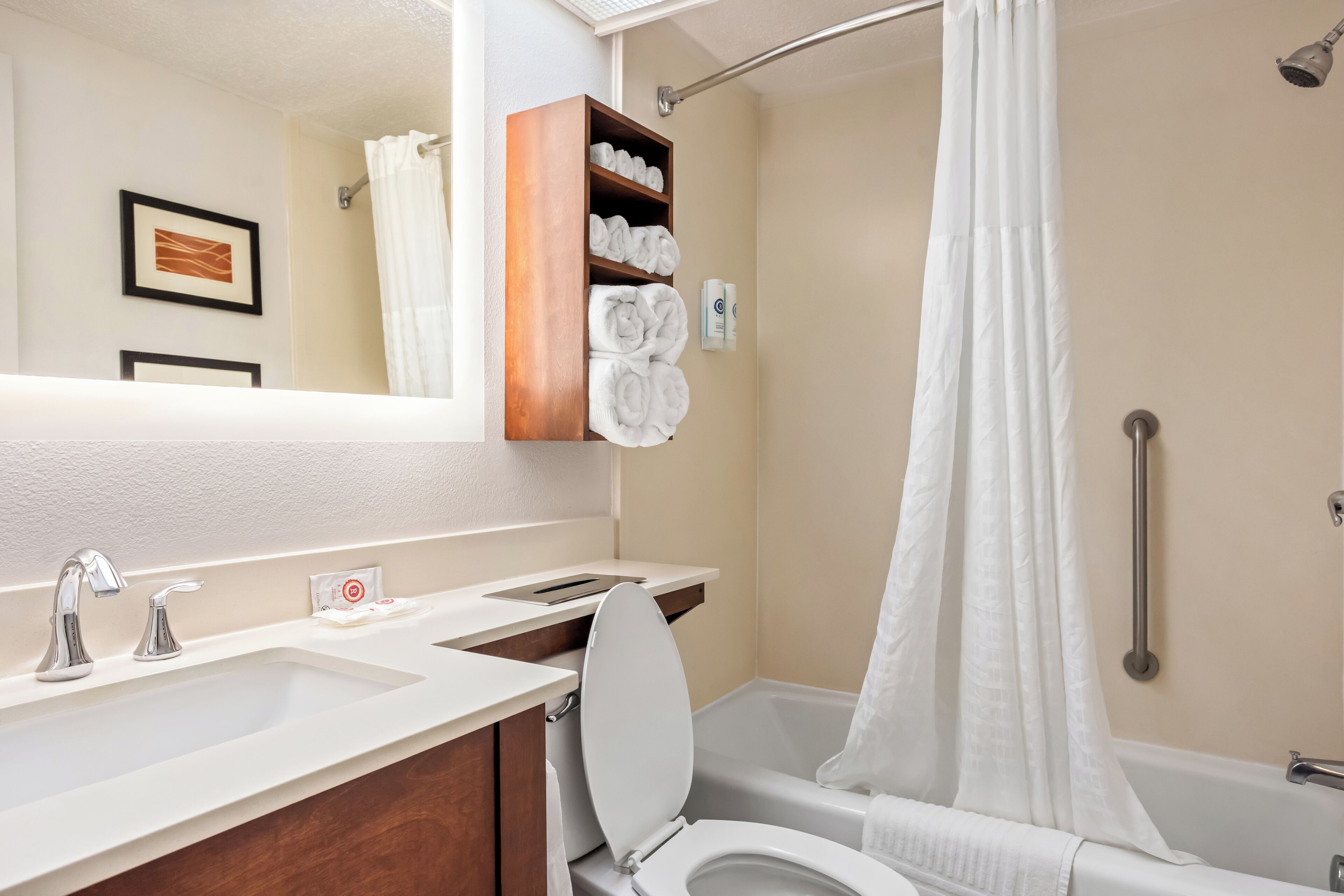 Une salle de bain avec un lavabo, des toilettes et une baignoire. Des serviettes sont suspendues sur un porte-serviettes et il y a un rideau de douche.