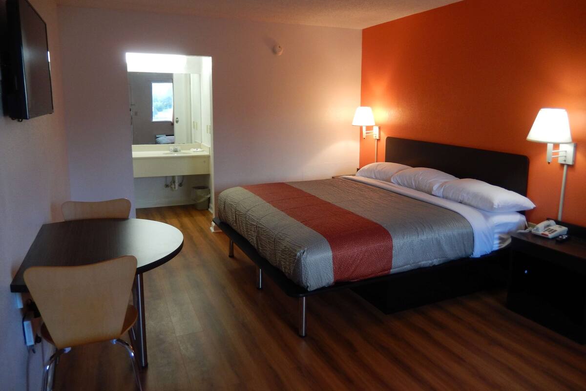 Ein Hotelzimmer mit Bett, Nachttischlampen, Schreibtisch und Stuhl.