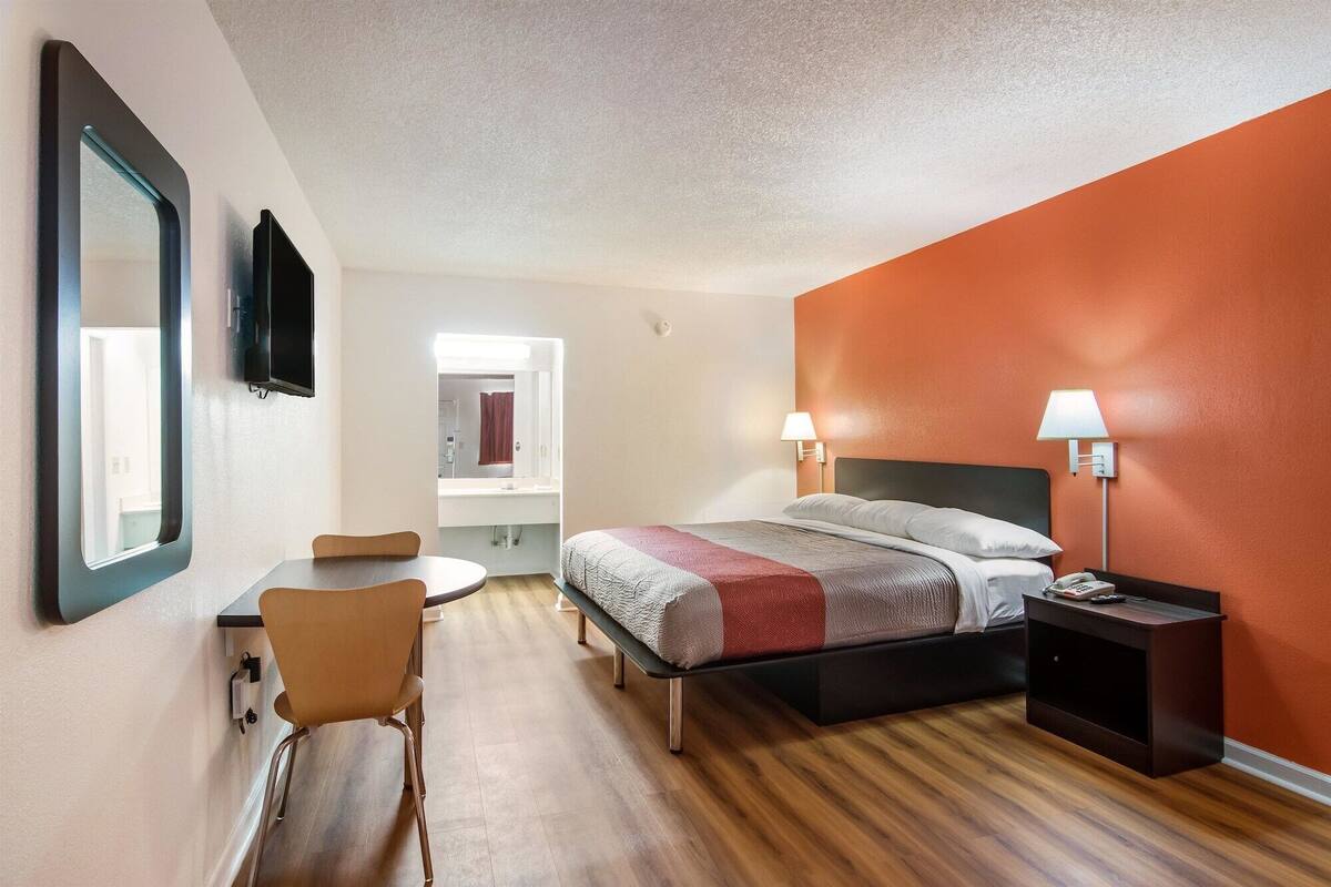 Ein Hotelzimmer mit einem Bett, Nachttischlampen, einem Schreibtisch und einem Stuhl.