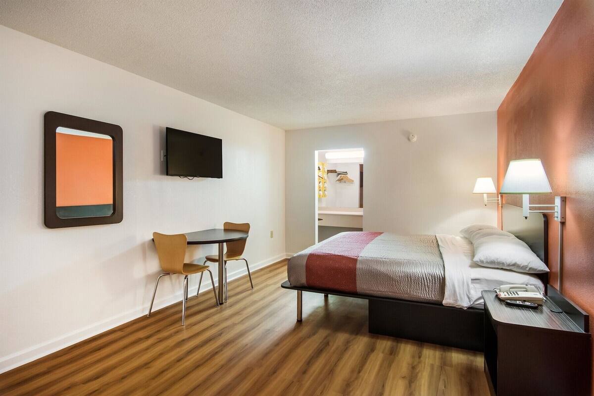 Ein Hotelzimmer mit Bett, Schreibtisch, Stuhl, Fernseher und Lampe.