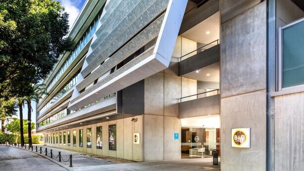 Un hôtel moderne doté d’une façade en verre, de plusieurs étages et d’une entrée bien visible.