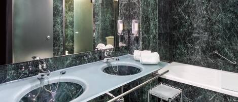 Un baño moderno con dos lavamanos, una bañera y un espejo grande.