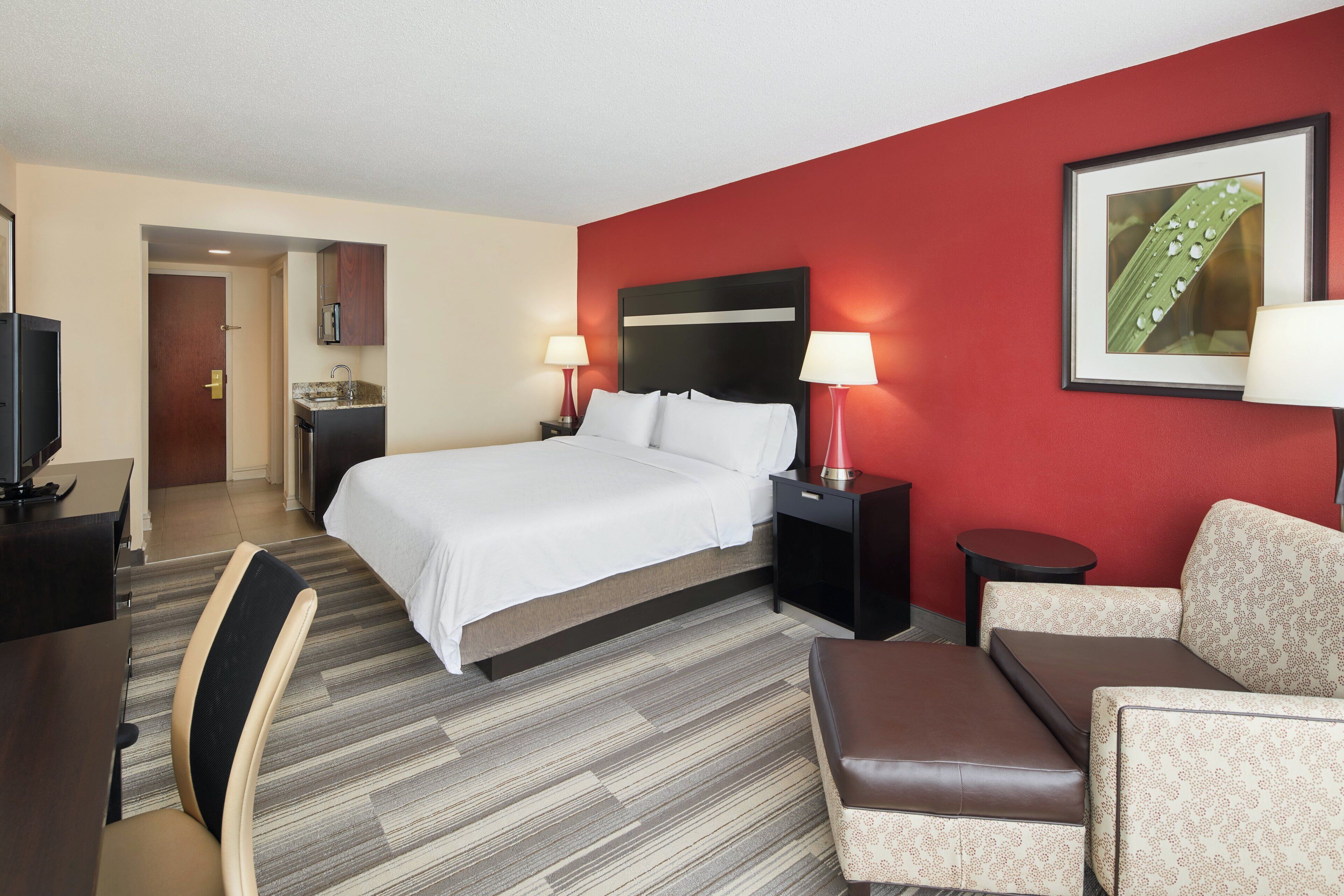 Une chambre d’hôtel comprenant un lit, des tables de chevet, un bureau, une chaise et un canapé.