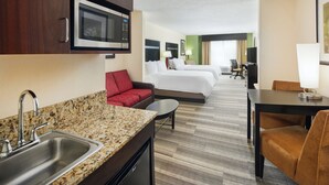 Hotelkamer met kitchenette, twee bedden, een rode bank en een eethoek.
