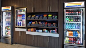 Een automaatruimte met diverse snacks en drankjes, zoals chips, frisdranken en water in flessen.