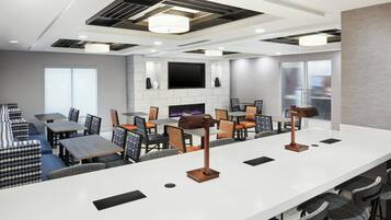 A modern hotel lobby with a bar area, seating arrangements, and a flat-screen TV mounted on the wall.
