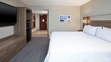 Habitación de hotel con una cama grande, un televisor de pantalla plana en la pared, un microondas y un armario de madera.