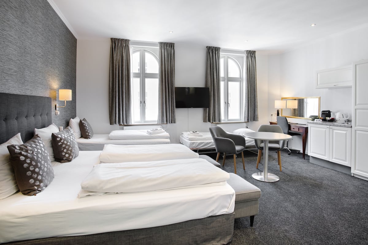 Habitación de hotel con una cama grande, un escritorio, una silla y un televisor.