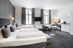 A hotel room with a large bed, a desk, a chair, and a TV.