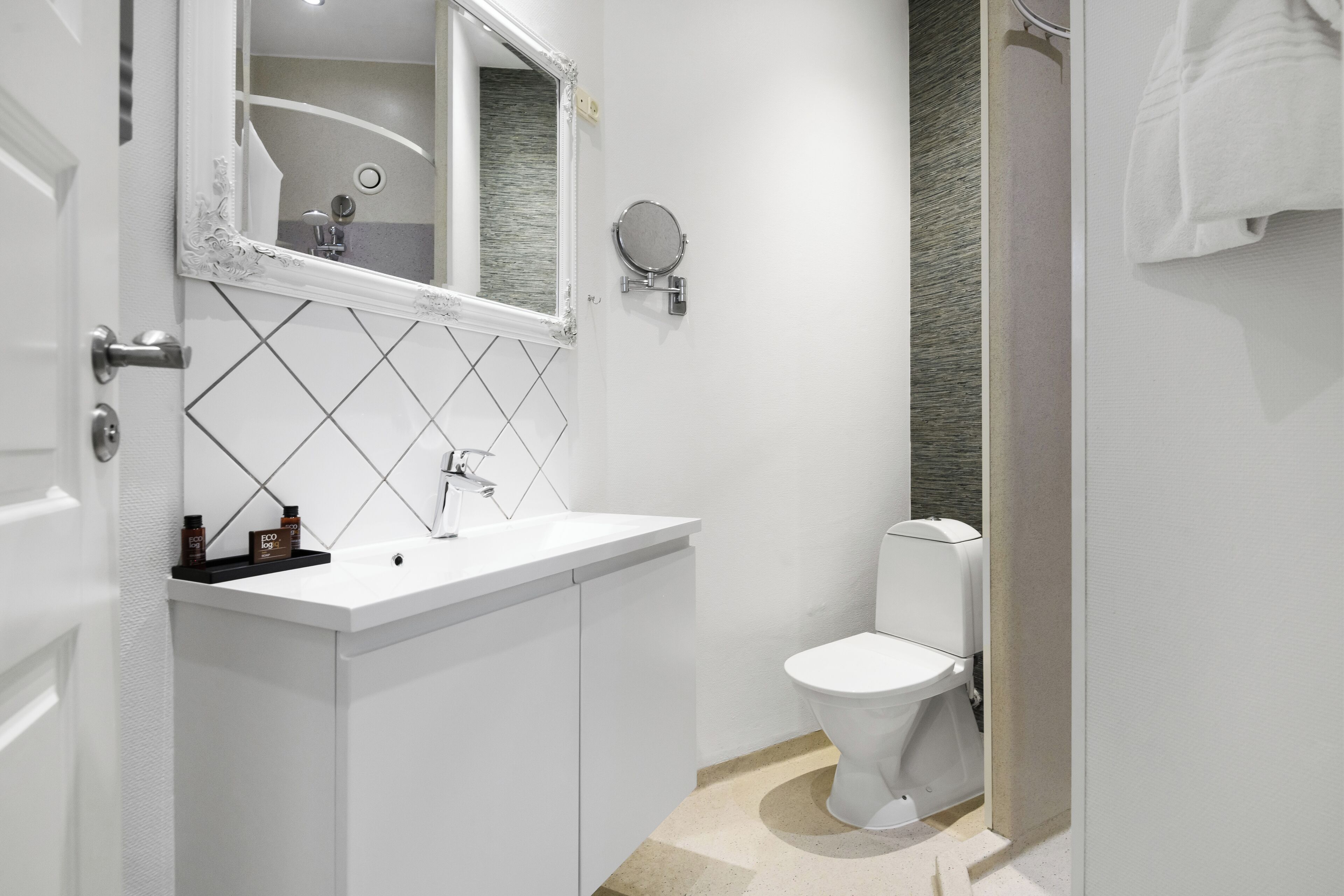 A modern bathroom with a white sink, mirror, and toilet.