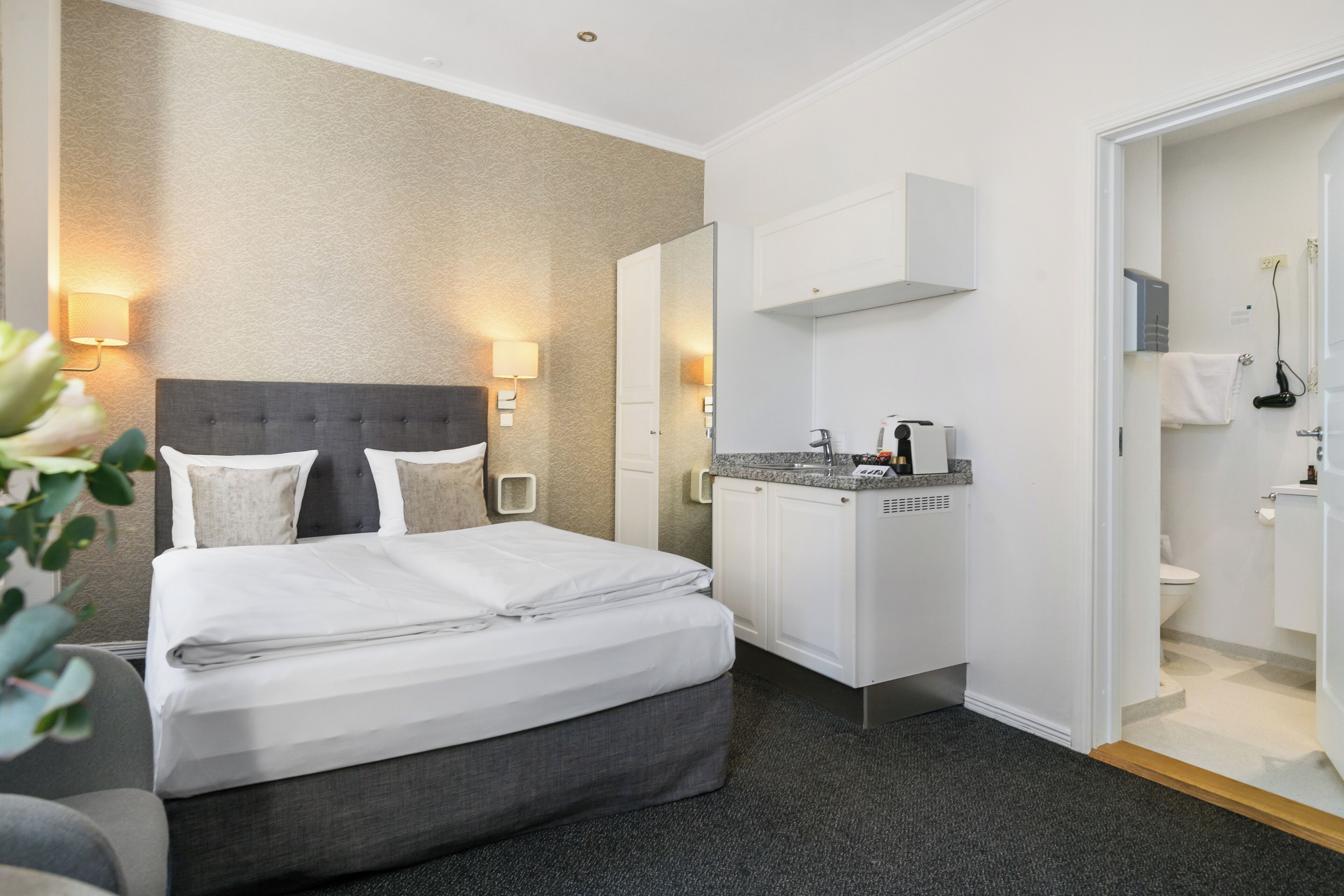 A hotel room with a bed, a bathroom, and a mirror.