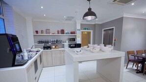 Una cocina moderna con estación de café, microondas y zona de comedor con sillas.