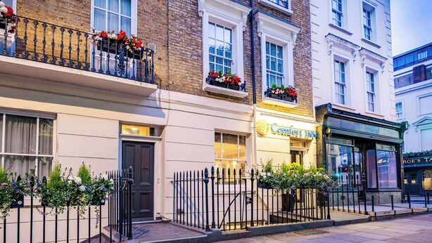 Un hotel con una fachada clásica, ventanas amplias y jardineras en los balcones.